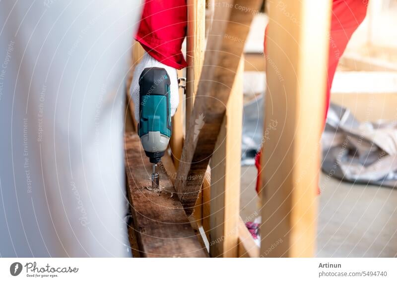 Techniker bohrt Holzkiste mit Bohrmaschine. Montage von schweren Maschinencontainern für den Transport. Techniker und Tischler tragen Schutzhandschuhe bei der Arbeit mit elektrischen Bohrmaschinen zum Bohren von Brettern.