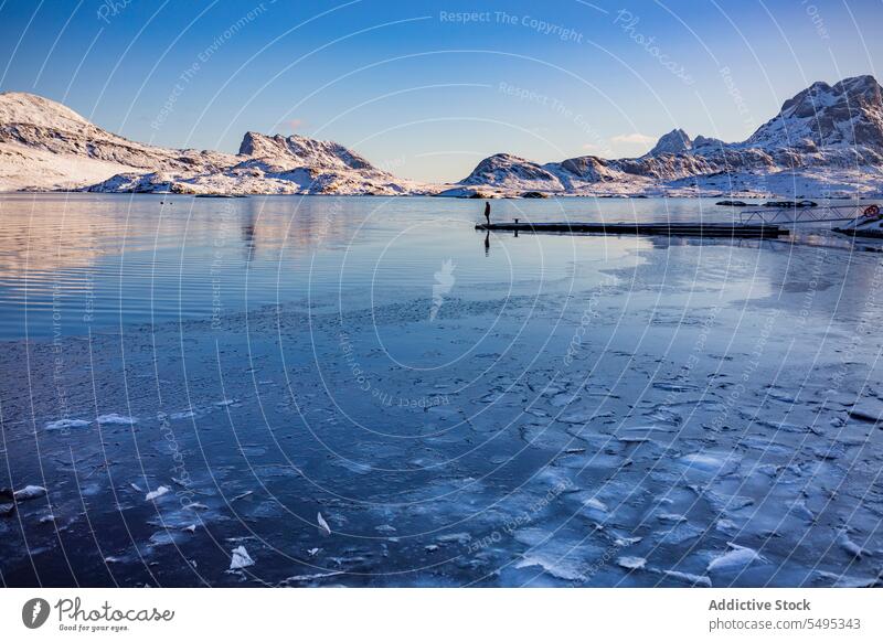 Kaltes Meer mit Tourist in Gebirgstal bei Tageslicht MEER Meereslandschaft Wasser Berge u. Gebirge Pier Eis Winter kalt Landschaft Meeresufer felsig Formation