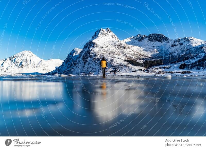 Niedriger Winkel Reisende stehen auf gefrorenen See in der Nähe von verschneiten Bergen Reisender Tourist Berge u. Gebirge Winter Schnee Natur lofoten Insel