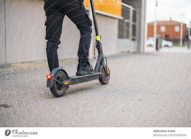 Anonymer Erntekurier, der mit einem Elektroroller auf der Straße fährt Auslieferer Kickroller elektrisch Mitfahrgelegenheit Verkehr Kurier Dienst Arbeiter