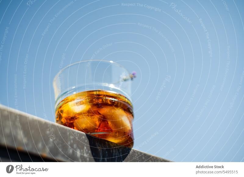 Glas Whiskey mit Eis und Orangenschalen vor blauem Himmel orange sich[Akk] schälen Container durchsichtig Unschärfe verschwommener Hintergrund Frucht trinken