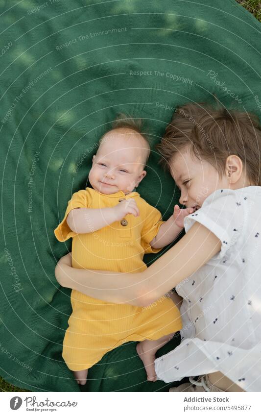 Niedlicher Bruder mit Baby-Geschwisterchen auf Decke im Park liegend Geschwisterkind Lügen Junge niedlich aussruhen Wochenende Zusammensein Lächeln Kinder