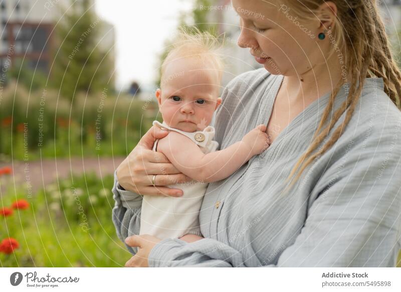 Frau trägt und umarmt süßes Baby im Park Mutter tragen umarmend niedlich Liebe Familie Blick Lifestyle Pflege klein bezaubernd Säugling Zusammensein