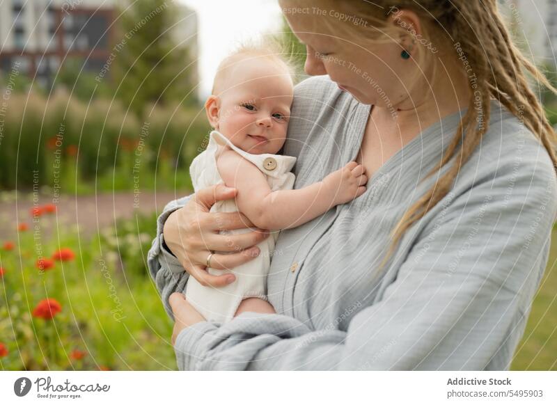 Frau trägt und umarmt süßes Baby im Park Mutter tragen umarmend niedlich Liebe Familie Blick Lifestyle Pflege klein bezaubernd Säugling Zusammensein