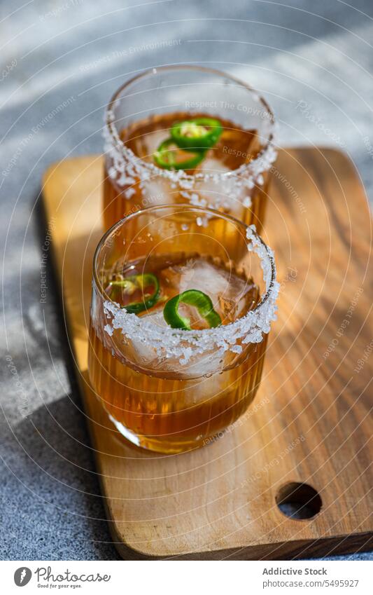 Japanischer Sochu-Likör mit Mangosaft und Jalapeno-Pfefferscheiben mit Salz am Glasrand Schnaps Saft Scheibe Paprika Saum traditionell trinken liquide Getränk