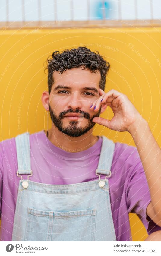 Junger bärtiger Mann schaut in die Kamera vor gelbem Hintergrund berühren selbstbewusst Gesicht berühren positiv traurig verärgert Schürze Stress Vollbart Unmut