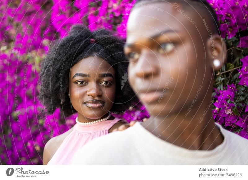 Schwarzes Teenagerpaar in der Nähe blühender Blumen Paar Afro-Look Zusammensein Frisur jung stehen Bonden trendy Freundin sorgenfrei krause Haare schwarz