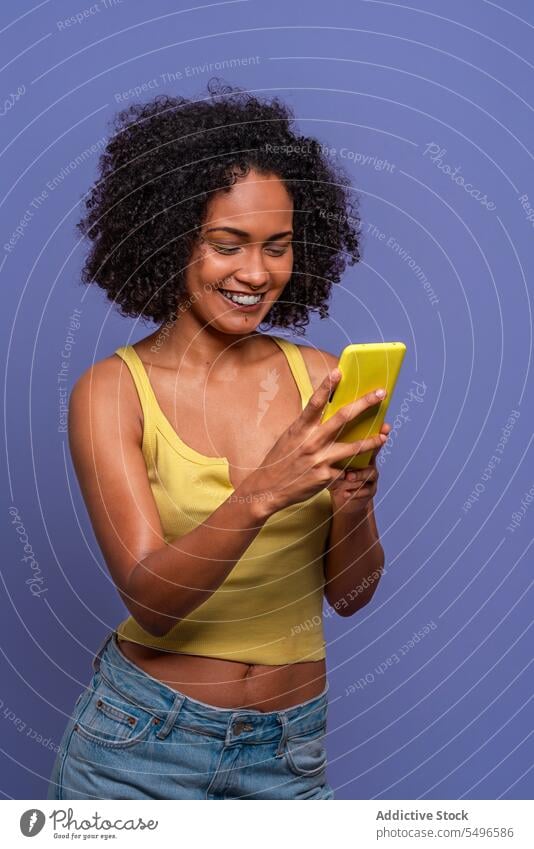 Glückliche ethnische Frau mit Mobiltelefon benutzend Smartphone online Lächeln heiter Browsen Afro-Look Apparatur Gerät krause Haare Internet Mobile Telefon