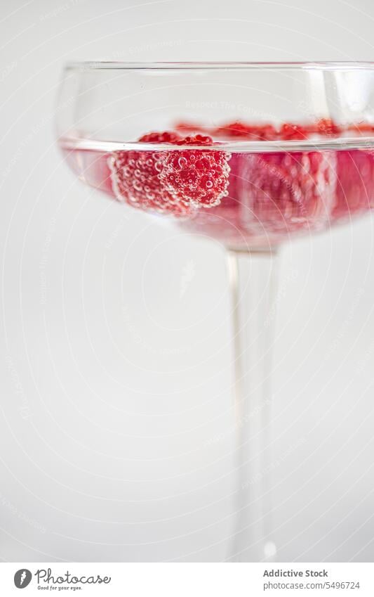 Glas Champagner und Himbeer-Cocktail gegen unscharfen Hintergrund frisch Himbeeren trinken Alkohol Erfrischung dienen Getränk reif Beeren Tisch kalt Vitamin