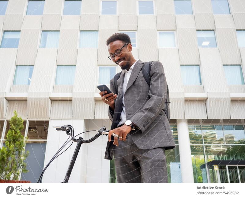 Schwarzer Geschäftsmann mit Smartphone und Fahrrad Mann Talkrunde formal Großstadt Straße Telefonanruf Browsen Anzug männlich Afroamerikaner schwarz Text urban