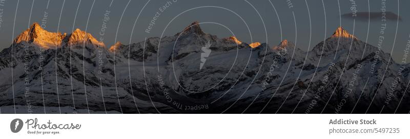 Verschneite Berge an einem Wintertag unter dunklem Himmel bei Sonnenaufgang Berge u. Gebirge Landschaft Schnee Natur felsig Gipfel malerisch Kamm kalt