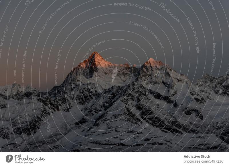 Verschneite Berge an einem Wintertag unter dunklem Himmel bei Sonnenaufgang Berge u. Gebirge Landschaft Schnee Natur felsig Gipfel malerisch Kamm kalt