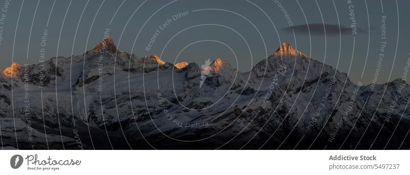 Verschneite Berge an einem Wintertag unter dunklem Himmel bei Sonnenaufgang Berge u. Gebirge Landschaft Schnee Natur felsig Gipfel malerisch Kamm kalt