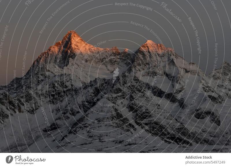 Verschneite Berge an einem Wintertag unter dunklem Himmel bei Sonnenaufgang Berge u. Gebirge Landschaft Schnee Natur felsig Gipfel malerisch Kamm kalt