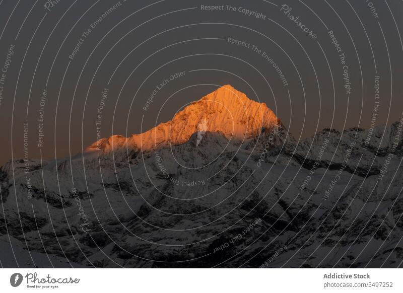 Verschneite Berge an einem Wintertag unter dunklem Himmel bei Sonnenaufgang Berge u. Gebirge Landschaft Schnee Natur felsig Gipfel malerisch Kamm kalt