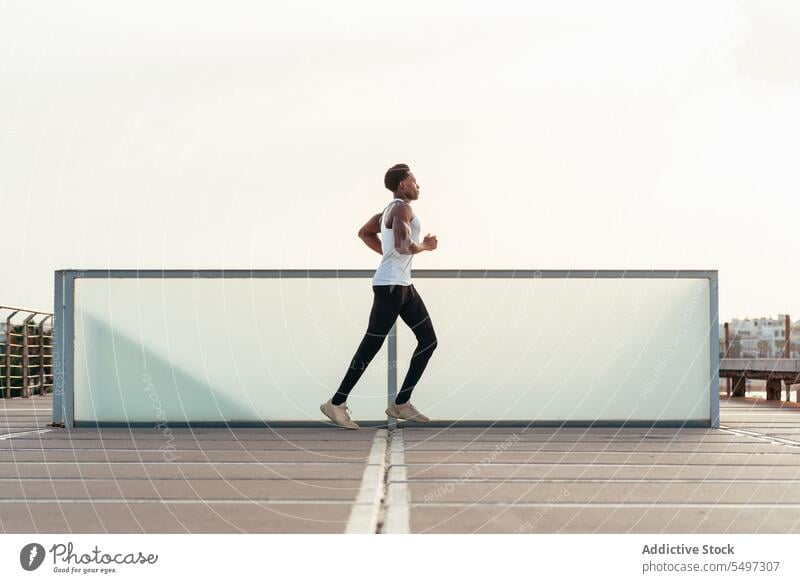 Schwarzer Sportler läuft auf Sportplatz Athlet joggen laufen Sportbekleidung Sportpark Aufwärmen Pier hölzern Übung männlich schwarz Afroamerikaner Model Herz