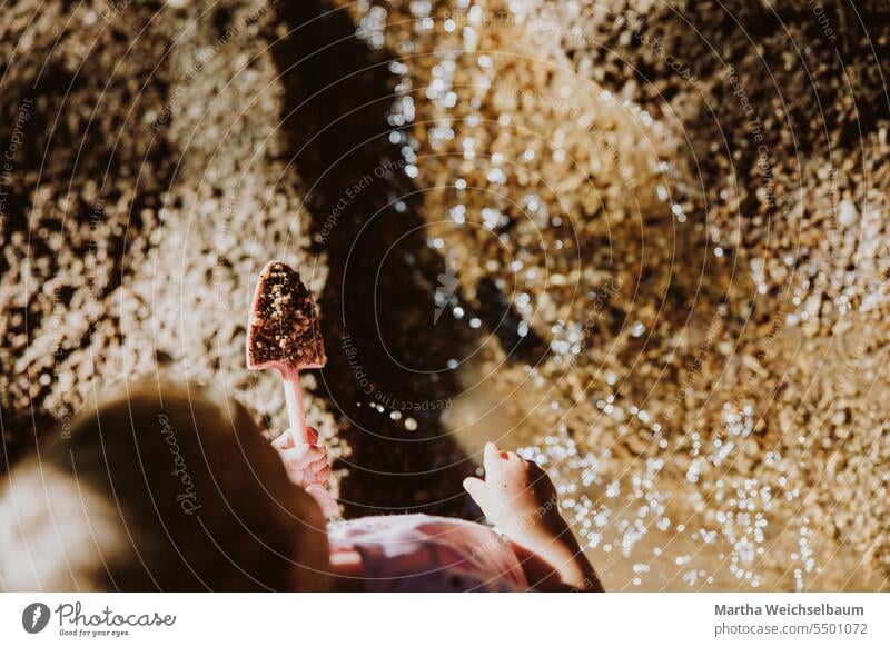 Kind spielt in Bach mit Sand und Kies Sandspiel Spielen im Freien spielen in der natur Spielen im Bach Natur Spielen mit Wasser Im Freien Sommer auf dem Land