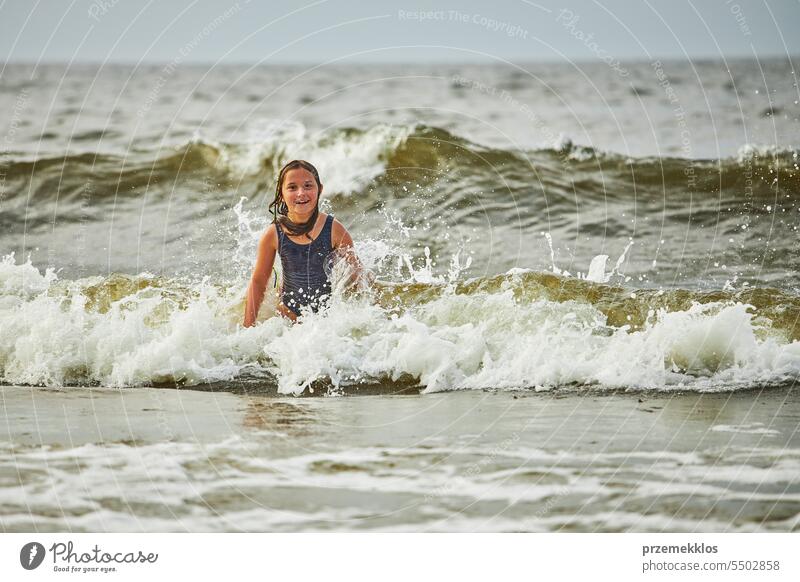 Kleines Mädchen spielt mit Wellen im Meer. Kind plantscht spielerisch in Wellen. Kind springt ins Meer. Urlaub am Strand. Wasser plätschert Sommer Ferien MEER