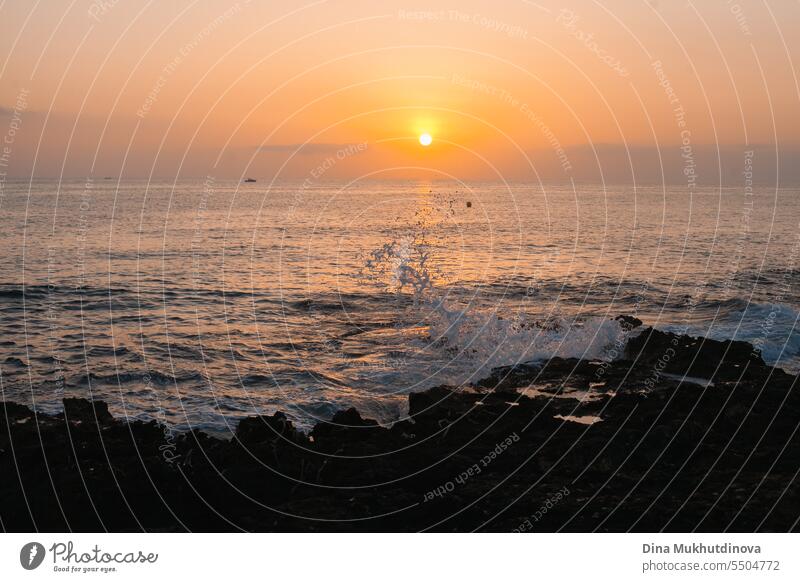 Sonnenaufgang über dem Meer im frühen Morgenlicht. Sonnenaufgang über dem Wasser am felsigen Strand. Sonnenuntergang Landschaft. Wasser plätschert mit Wellen.