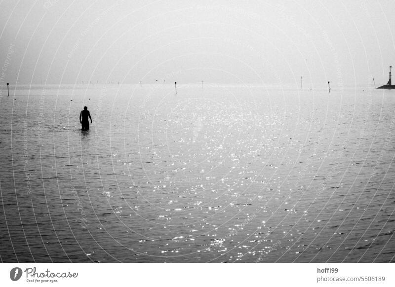 ein Mensch schreitet am Meer durch flaches Wasser - der Morgen ist ruhig , wer weiß was noch so passiert schreiten waten Wattenmeer seichtes Wasser