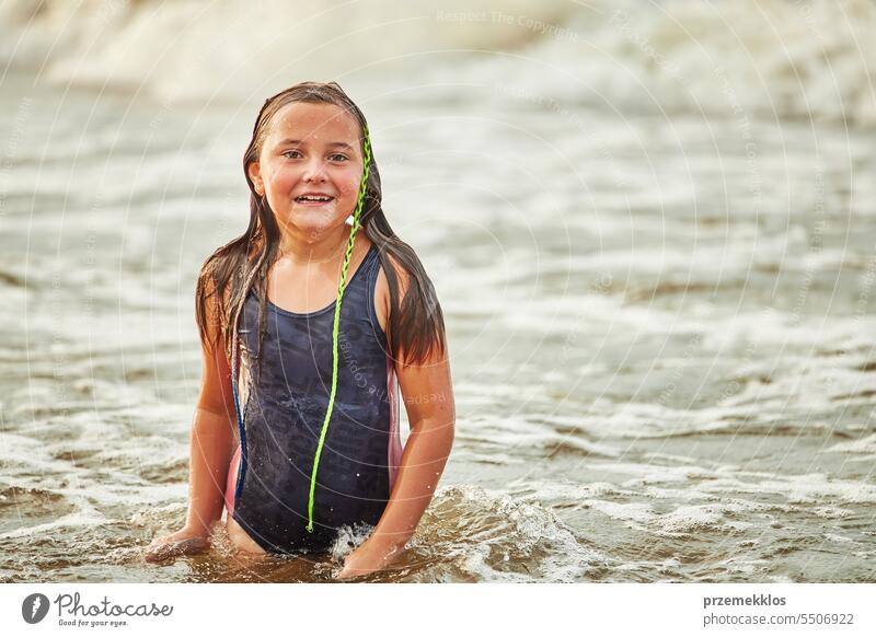 Kleines Mädchen spielt mit Wellen im Meer. Kind plantscht spielerisch in Wellen. Kind springt ins Meer. Urlaub am Strand. Wasser plätschert Sommer Ferien MEER