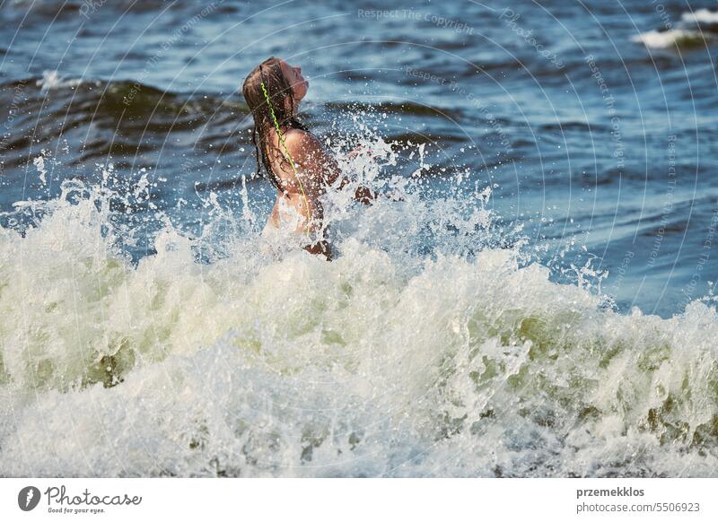 Kleines Mädchen spielt mit Wellen im Meer. Kind plantscht spielerisch mit Wellen. Kind springt in Meereswellen. Sommerurlaub am Strand Ferien MEER Spielen