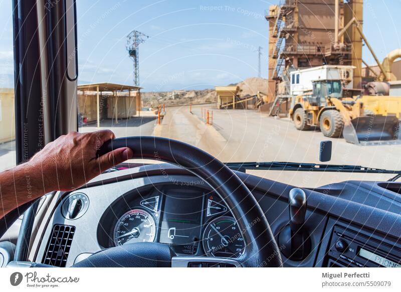 Blick aus der Fahrerposition eines Lastwagens bei der Einfahrt in ein Aggregatewerk mit Waage und Industriemaschinen. im Inneren Ansicht Brückenwaage Lenkrad