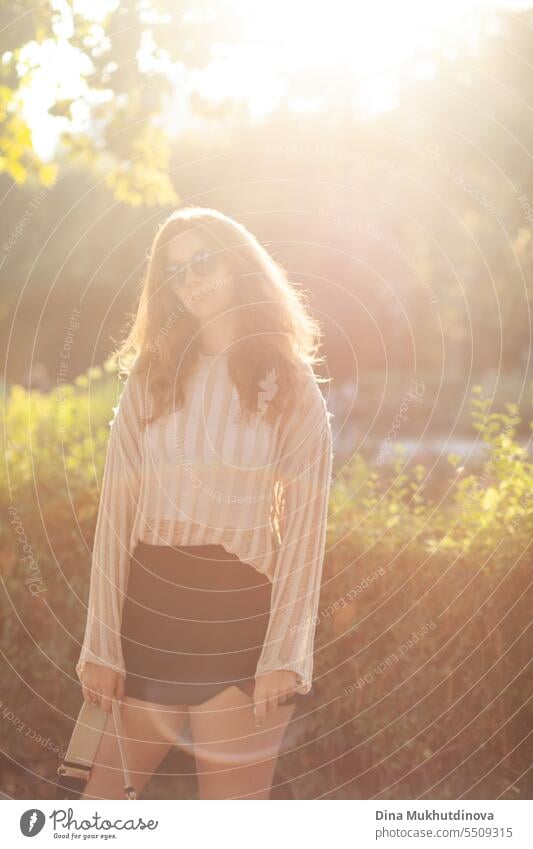 candid Porträt der jungen schönen Frau mit Sonnenbrille im Gegenlicht mit Sonnenlicht im Sommer. Hübsches rothaariges Mädchen mit roten Haaren. Park Lächeln