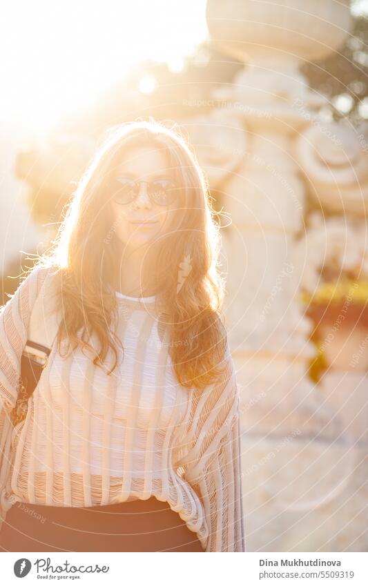 candid Porträt der jungen schönen Frau mit Sonnenbrille im Gegenlicht mit Sonnenlicht im Sommer. Hübsches rothaariges Mädchen mit roten Haaren. Park Lächeln