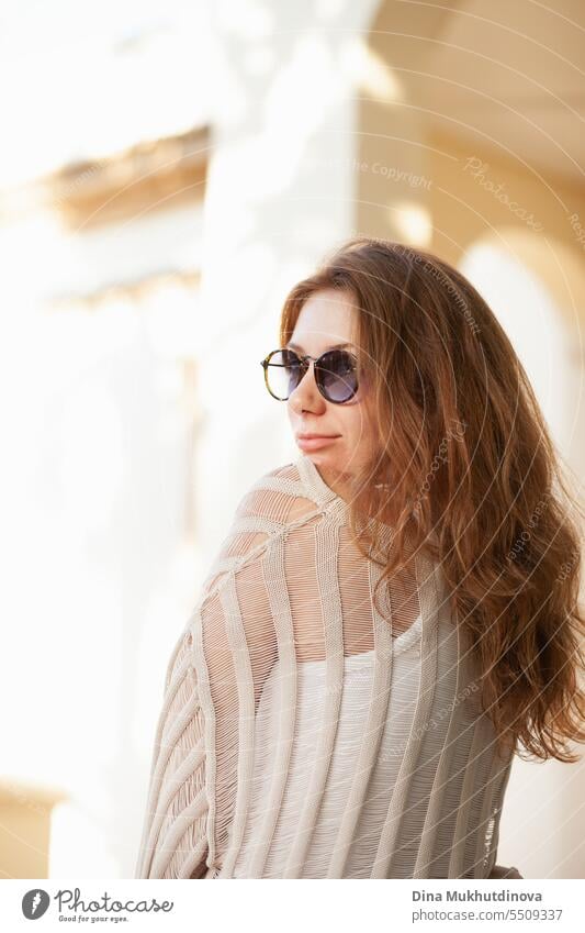 Junge schöne rothaarige Frau in Freizeitkleidung mit Sonnenbrille auf neutralem beigem Hintergrund. Candid Outdoor-Porträt im Park. Mädchen jung junges Mädchen