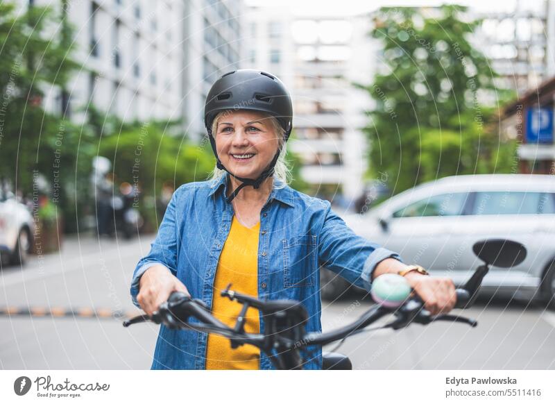 Porträt einer älteren Frau mit Helm beim Fahrradfahren in der Stadt Menschen Kaukasier Stehen Gesundheit Stadtleben graues Haar genießen Straße lässig Tag