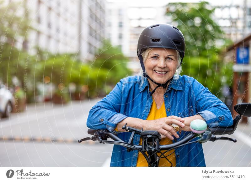 Porträt einer älteren Frau mit Helm beim Fahrradfahren in der Stadt Menschen Kaukasier Stehen Gesundheit Stadtleben graues Haar genießen Straße lässig Tag