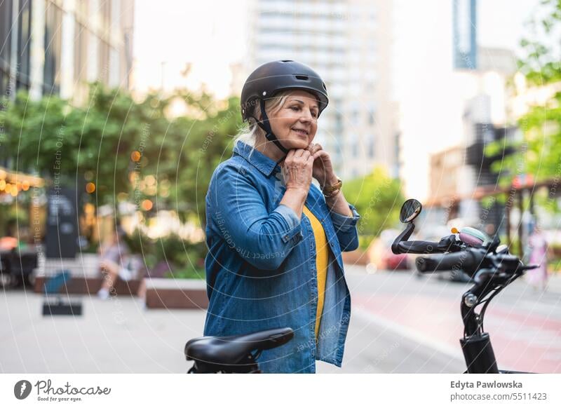 Porträt einer älteren Frau mit Helm beim Fahrradfahren in der Stadt Menschen Kaukasier Stehen Gesundheit Stadtleben graues Haar genießen Straße lässig Tag