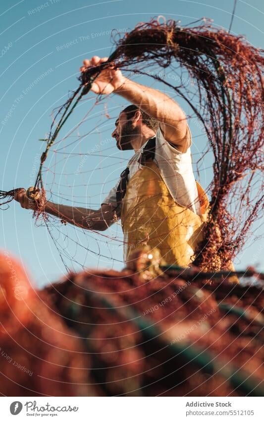 Mann, der ein Netz aus einem Segelboot im Meer zieht Fischer ziehen Fischen aufbinden Boot Trawler Schürze männlich Soller Balearen Mallorca Wadenfisch jagen