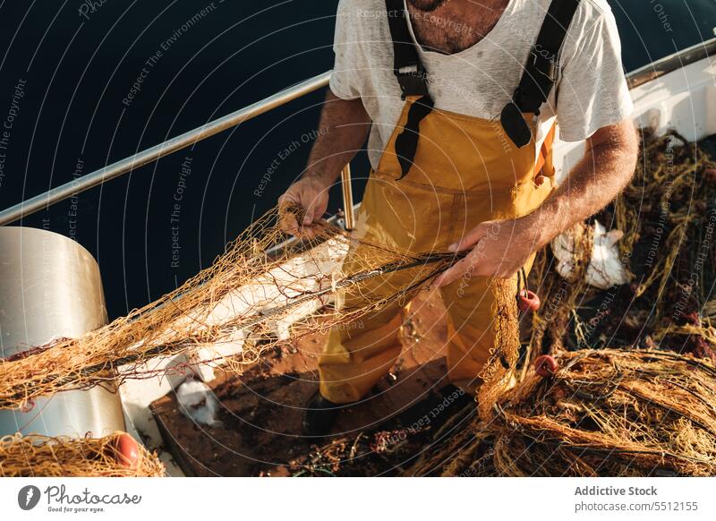 Anonymer Fischer, der vom Segelboot aus im offenen Meer fischt Boot MEER Fischen Netz Schoner Arbeit Uniform Fokus männlich Soller Balearen Mallorca Wadenfisch