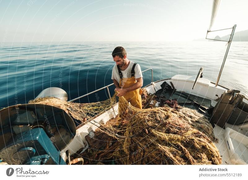 Fischer, der vom Segelboot aus im offenen Meer fischt Boot MEER Fischen Netz Schoner Arbeit Uniform Fokus männlich Soller Balearen Mallorca Wadenfisch jagen