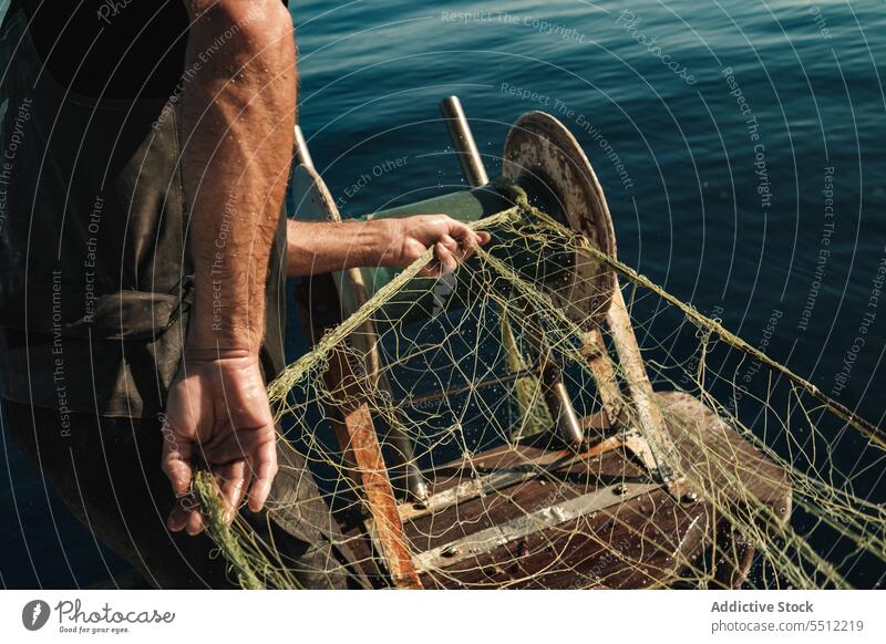 Anonymer Fischer, der vom Segelboot aus im offenen Meer fischt Boot MEER Fischen Netz Schoner Arbeit Uniform Fokus männlich Soller Balearen Mallorca Wadenfisch