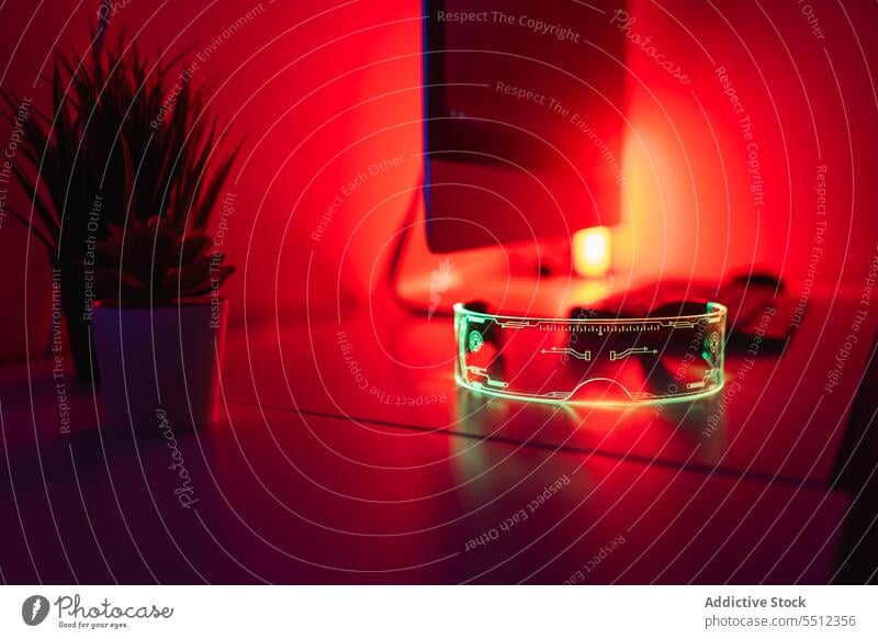 Desktop-Monitor mit Tastatur AR-Brille und leuchtend rotes Neonlicht auf dem Schreibtisch Arbeitsplatz Computer Keyboard neonfarbig Pflanze glühen Raum modern