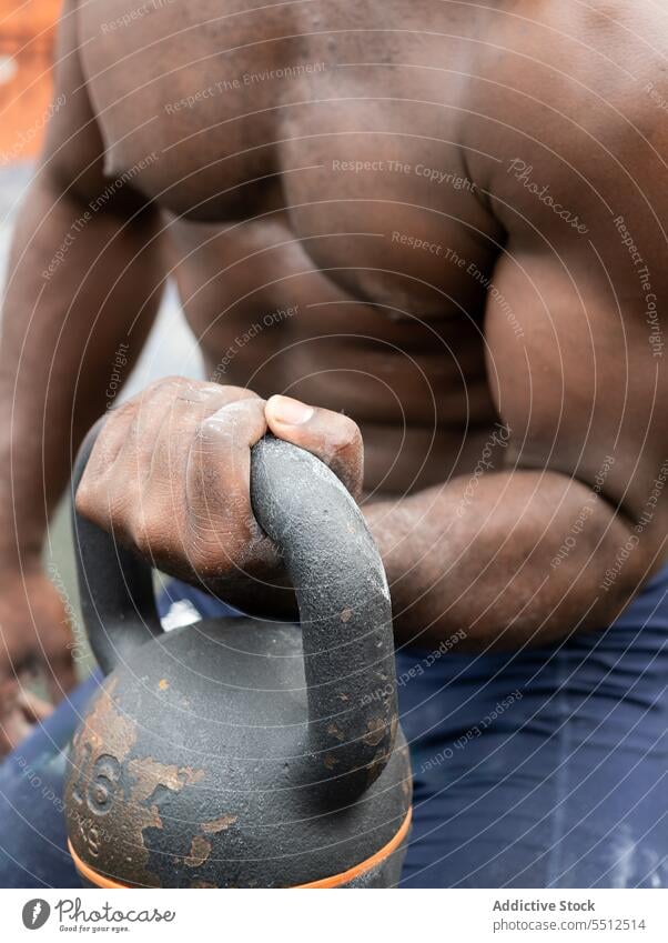 Nicht erkennbarer muskulöser ethnischer Mann beim Training mit Kettlebell im Tageslicht Übung Athlet stark schwer ohne Hemd Gewicht männlich Sportler