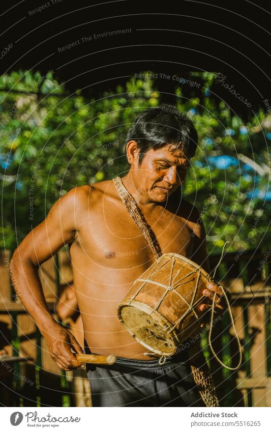 Einheimischer Mann spielt Trommel im Sonnenlicht Stamm Dorf spielen lokal einheimisch ländlich Spaziergang heimatlich authentisch Natur tropisch Tradition