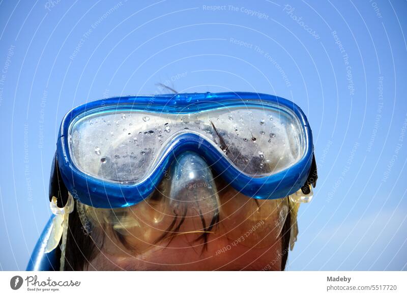 Junge mit blauer Taucherbrille und Schnorchel vor blauem Himmel im Sonnenschein am Strand von Sarimsakli bei Ayvalik am Ägäischen Meer in der Provinz Balikesir in der Türkei