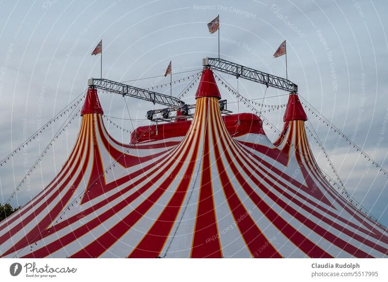 Dach eines  rot-weiß gestreiften Zirkuszelts mit wehenden Fahnen Zikuszelte Zelt Himmel Show Veranstaltung Kultur Jahrmarkt Spitze Freizeit & Hobby Wolken