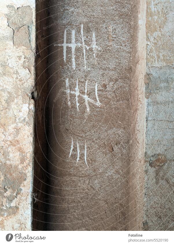 In eine schmutzige, verputzte Wand wurden Striche eingeritzt. Es sieht aus, als hätte hier ein Gefangener die Tage gezählt. Putz lost places alt dreckig braun