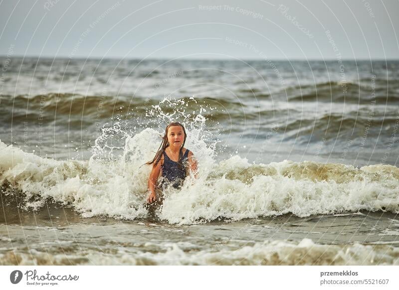 Kleines Mädchen spielt mit Wellen im Meer. Kind plantscht spielerisch in Wellen. Kind springt ins Meer. Urlaub am Strand. Wasser plätschert Sommer Ferien MEER