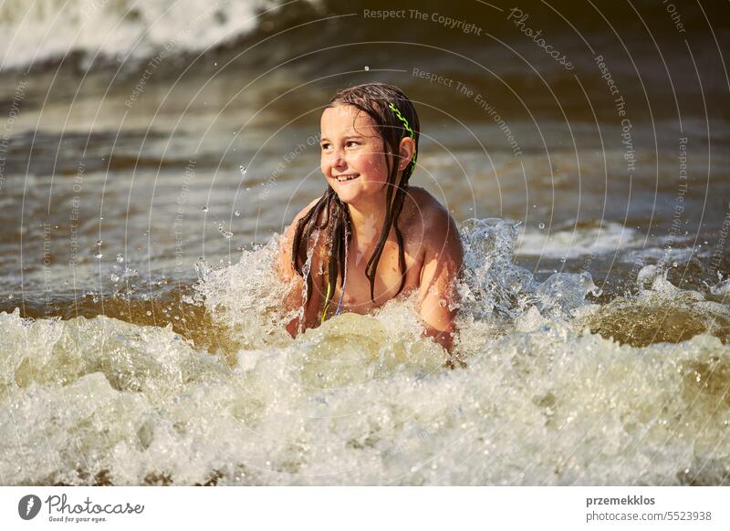 Kleines Mädchen spielt mit Wellen im Meer. Kind plantscht spielerisch mit Wellen. Kind springt in Meereswellen. Sommerurlaub am Strand Ferien MEER Spielen