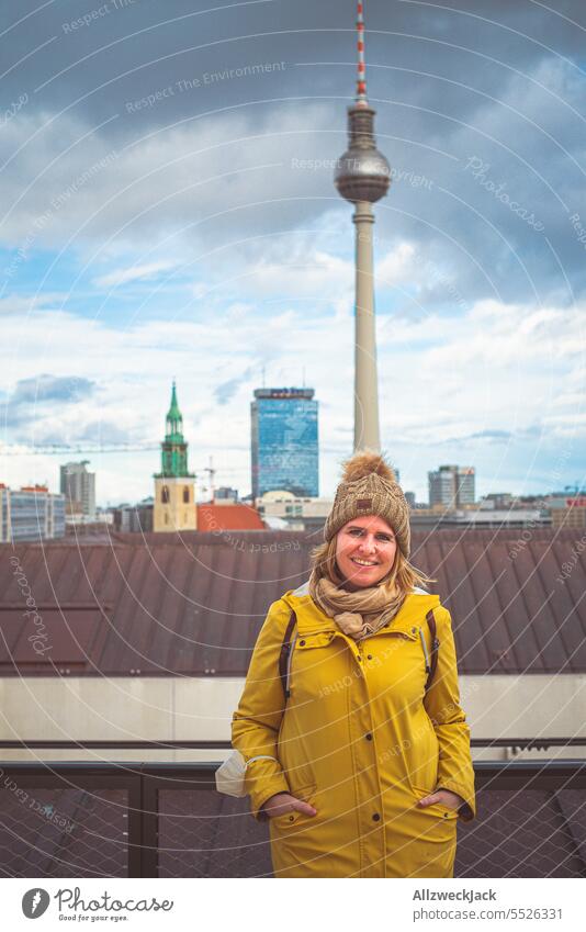 Portrait einer jungen blonden Frau mit herbstlicher Kleidung und Pudelmütze vor dem Fernsehturm Berlin Berlin-Mitte Berliner Fernsehturm park inn Hotel Skyline