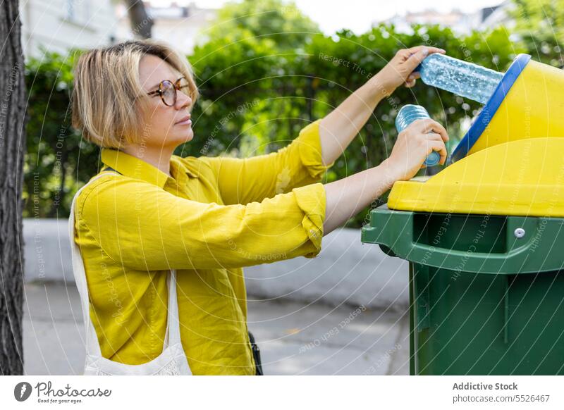 Frau wirft Müll in die gelbe Tonne wiederverwerten Kunststoff führen Ökologie Problematik lässig Tageslicht Abfall Container reduzieren Paket gebrauchen Trödel