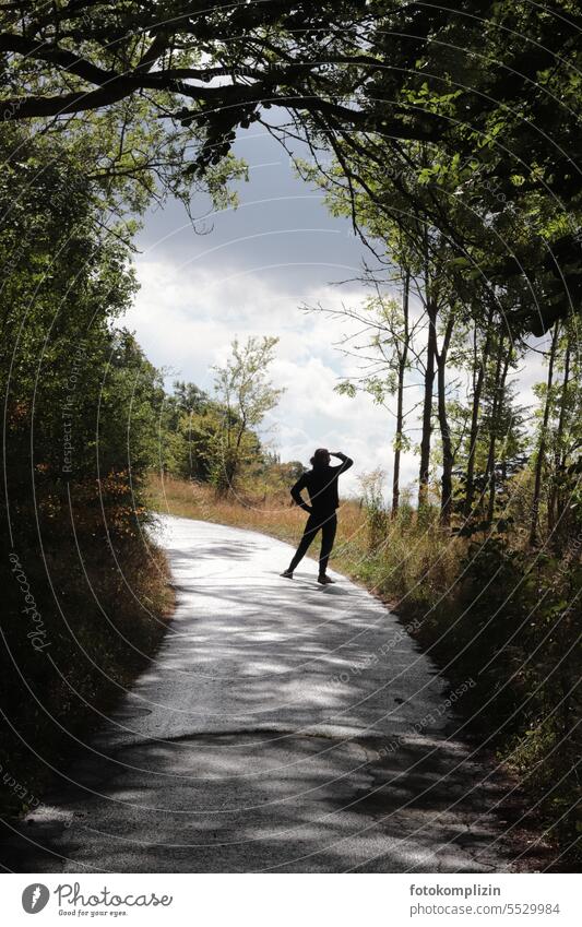 Person steht auf einem Weg und schaut in die Ferne Mensch Zukunft schauen Blick Weitblick Weitsicht Natur Landschaft spazieren Spaziergänger schauend Ausflug