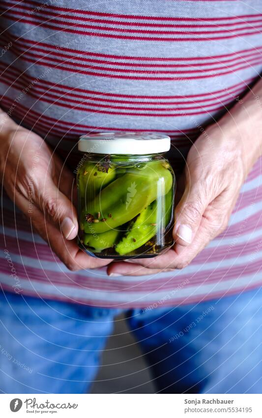 Ein Mann mit einem Einmachglas eingelegter Paprika. Nahaufnahme. Essig Hände halten Gemüse Ernährung Farbfoto Gesunde Ernährung Bioprodukte Foodfotografie Diät