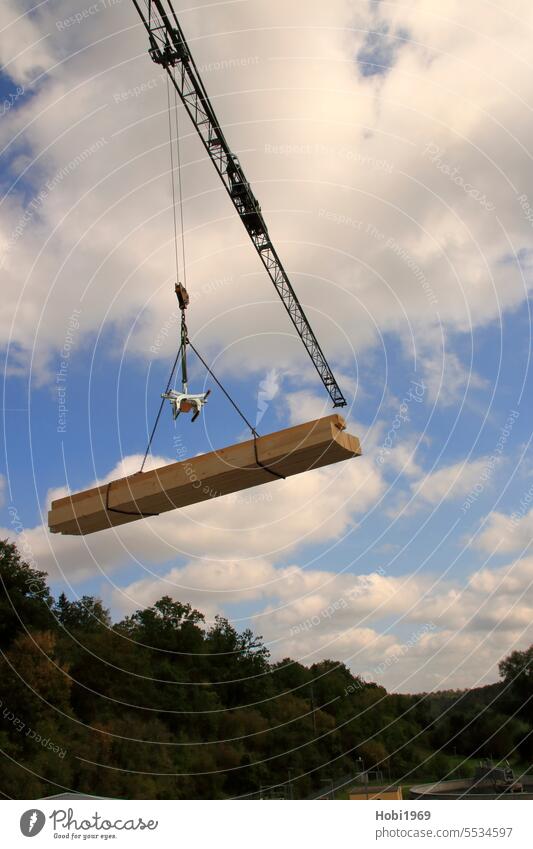 Holzbalken werden mit einem Kran durch die Luft transportiert Balken Transport transportieren Gefahr Gefährlich Helm Sicherheit Sicherung absichern stürzen